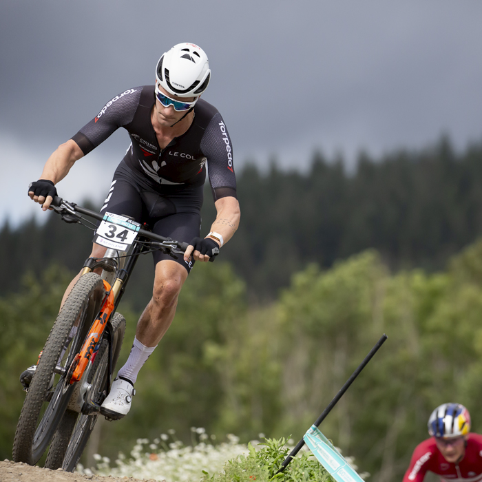 2023 UCI Cycling World Championships - Mountain Bike - Elite Men - Sam Gaze of New Zealand takes on a descent with a glowering sky behind