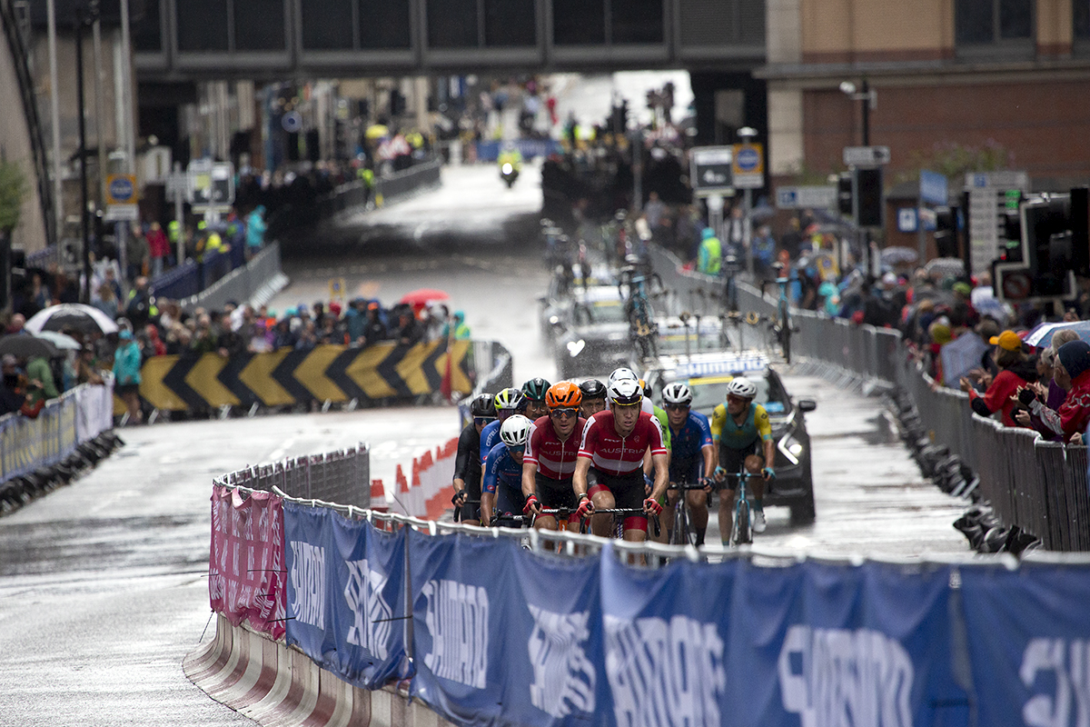 2023 UCI Cycling World Championships - Road Race - Elite Men - A group of riders on Cathedral Street followed by the race convoy