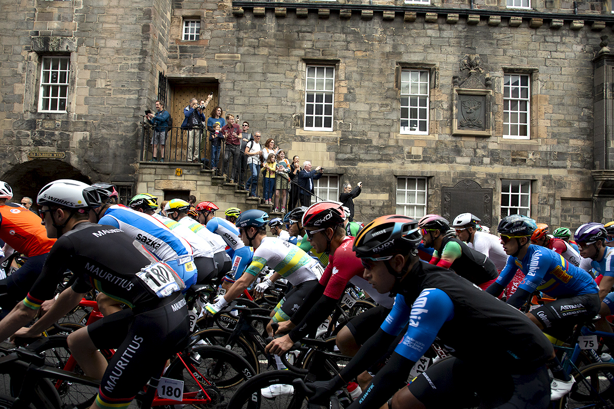 2023 UCI Cycling World Championships - Road Race - Elite Men - Riders make their way up Cannongate in Edinburgh as spectators stand on the steps of a building to gain a vantage point