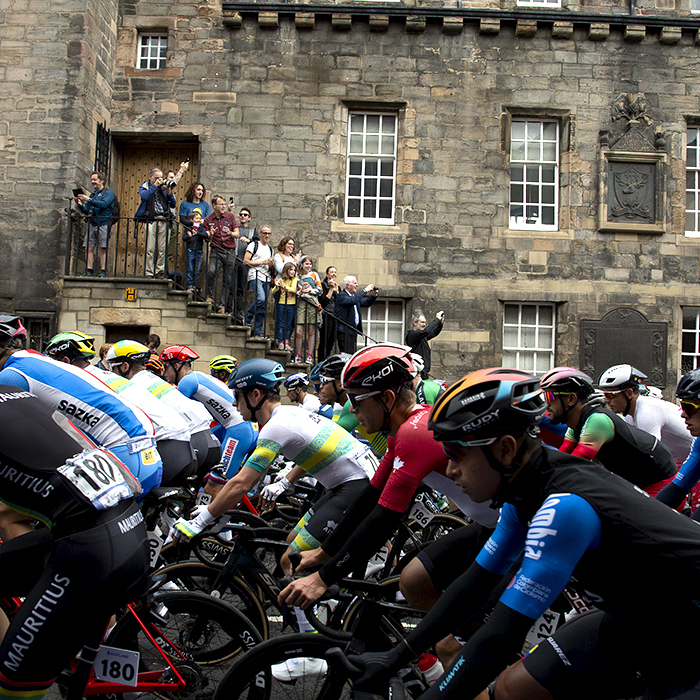 2023 UCI Cycling World Championships - Road Race - Elite Men - Riders make their way up Cannongate in Edinburgh as spectators stand on the steps of a building to gain a vantage point