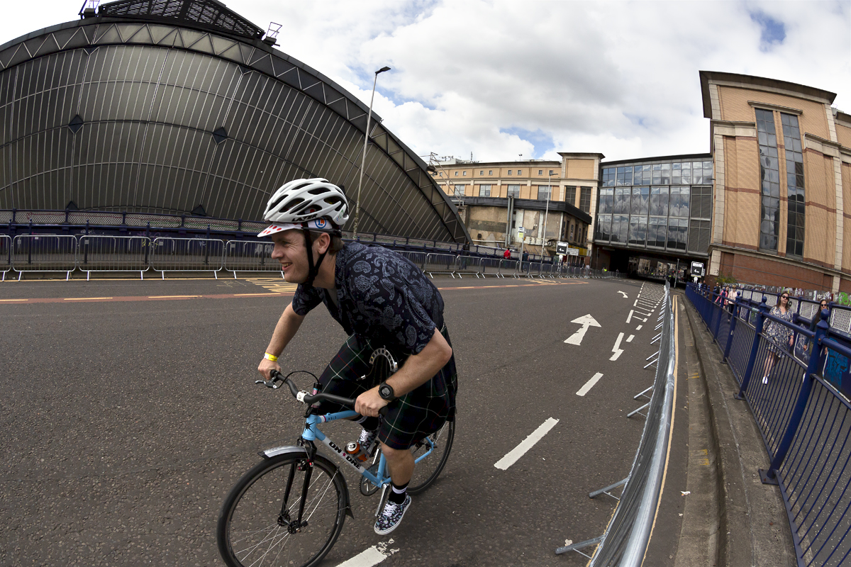 2023 UCI Cycling World Championships - Road Race - Elite Men - A fan dressed in a kilt rides a bike with a can of IRN-BRU in the bottle cage past Glasgow Queen Street station