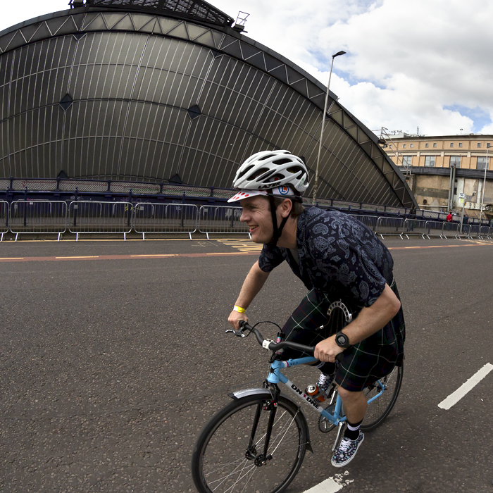 2023 UCI Cycling World Championships - Road Race - Elite Men - A fan dressed in a kilt rides a bike with a can of IRN-BRU in the bottle cage past Glasgow Queen Street station