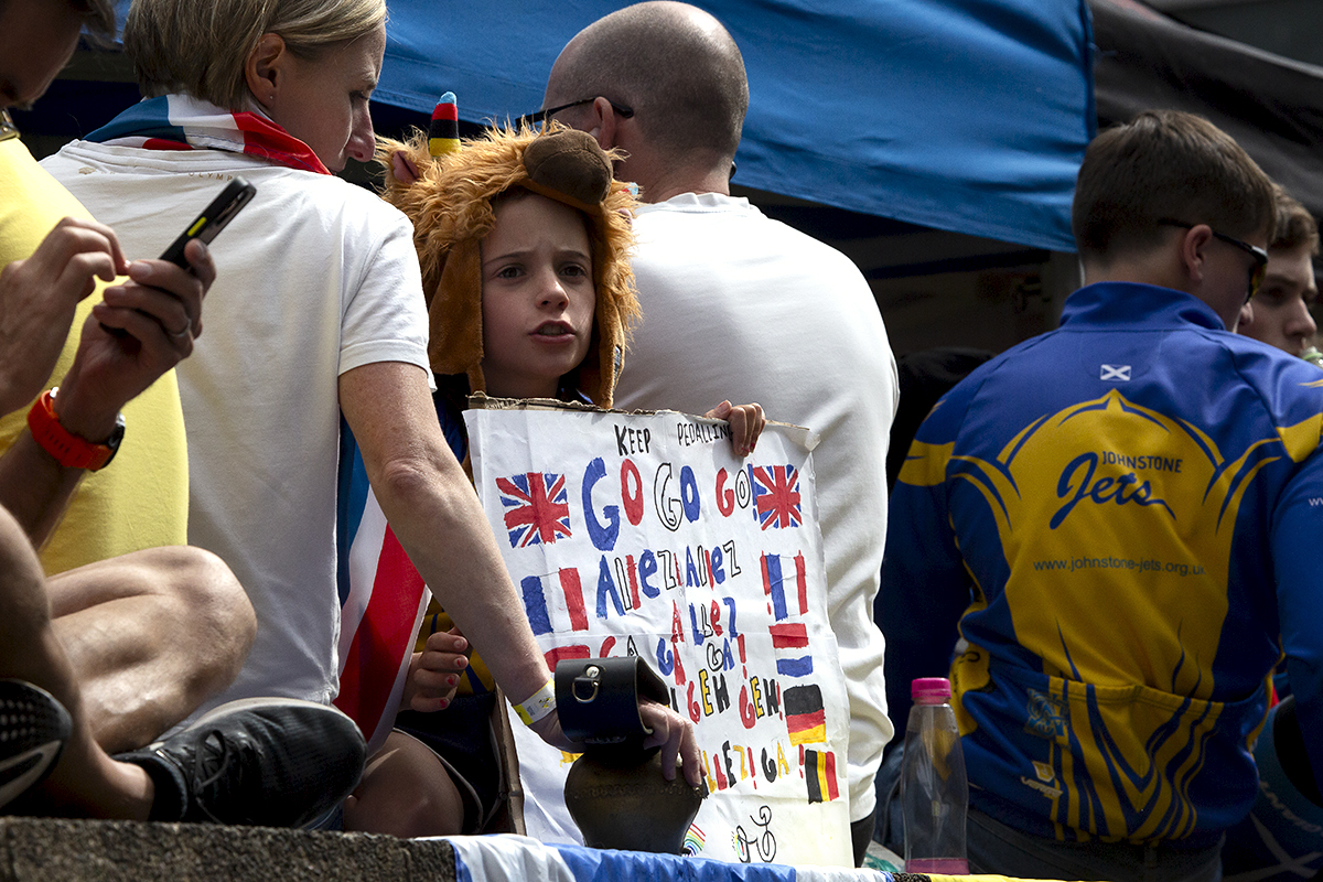 2023 UCI Cycling World Championships - Road Race - Elite Men - A young fan wearing a cow hat holds a multi-lingual sign as they wait for the race