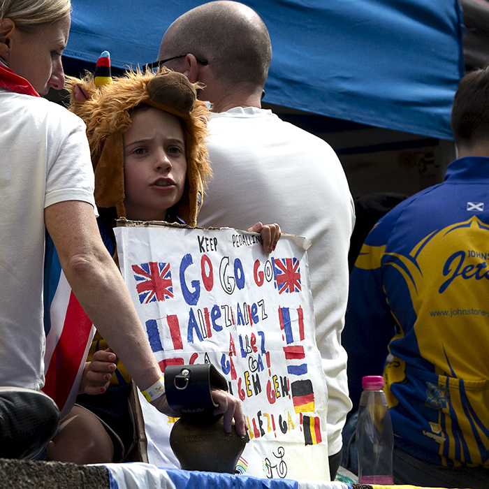 2023 UCI Cycling World Championships - Road Race - Elite Men - A young fan wearing a cow hat holds a multi-lingual sign as they wait for the race