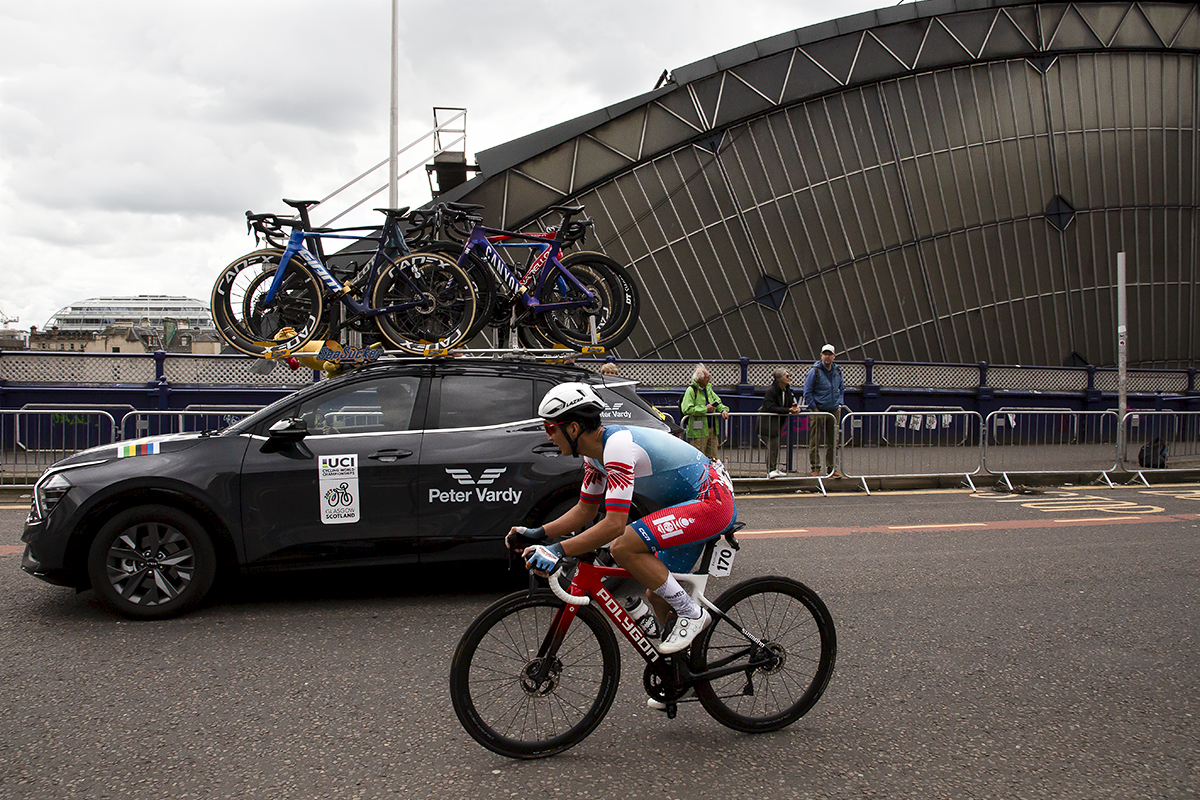 2023 UCI Cycling World Championships - Road Race - Elite Men - Jambaljamts Sainbayar of Mongolia accompanied by a team car passes the glass arch of Glasgow Queen Street station