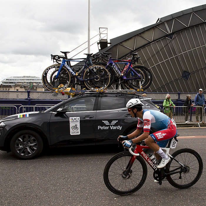 2023 UCI Cycling World Championships - Road Race - Elite Men - Jambaljamts Sainbayar of Mongolia accompanied by a team car passes the glass arch of Glasgow Queen Street station