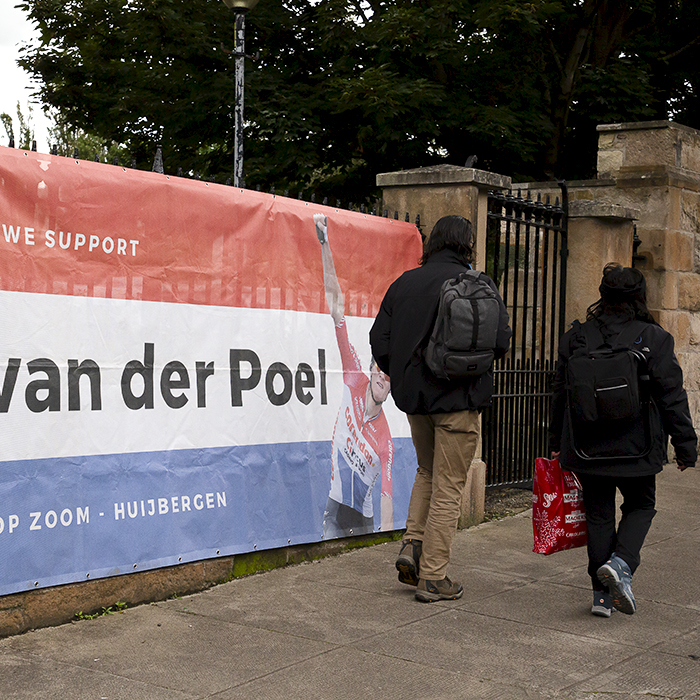 2023 UCI Cycling World Championships - Road Race - Elite Men - Two people walk past a giant banner hung from railings dedicated to Mathieu van der Poel of the Netherlands