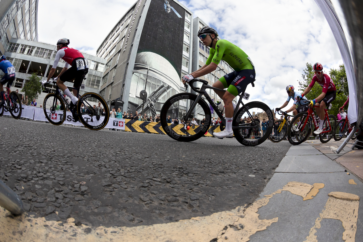 2023 UCI Cycling World Championships - Road Race - Elite Men - Tadej Pogačar of Slovenia rounds a corner past a mural depicting a satellite