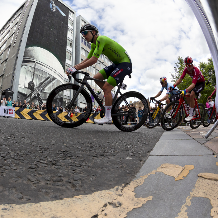 2023 UCI Cycling World Championships - Road Race - Elite Men - Tadej Pogačar of Slovenia rounds a corner past a mural depicting a satellite