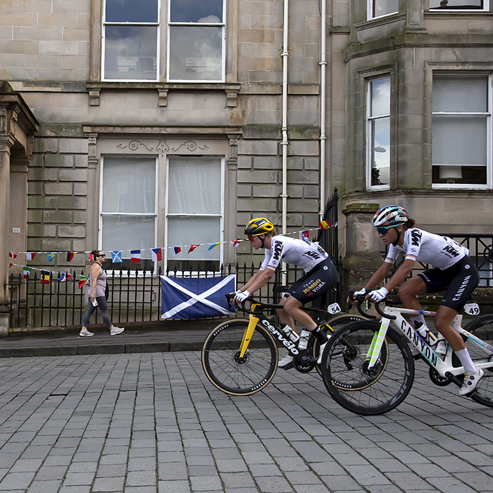 2023 UCI Cycling World Championships - Road Race - Elite Women - The race passes grand stone buildings with bunting and a Scottish flag in the background