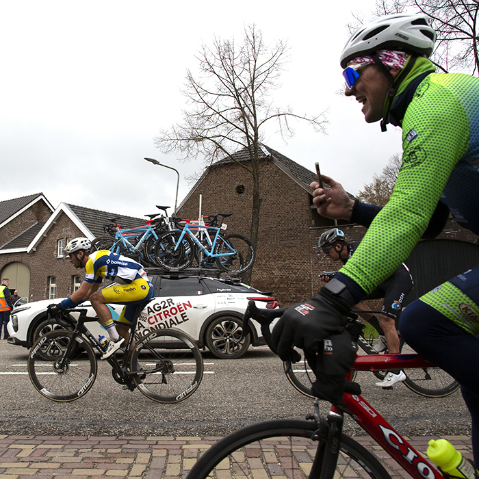 Amstel Gold Race 2023 - A fan follows the race on his bike filming on his mobile phone from the cycle path