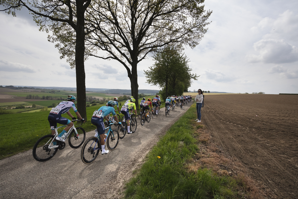 Amstel Gold Race 2024 - Riders pass trees and an open view on Heugdenweg as a fan watches on