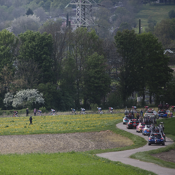 Amstel Gold Race 2024 - The race seen from a distance on Scheumerweg as team cars snake their way in pursuit