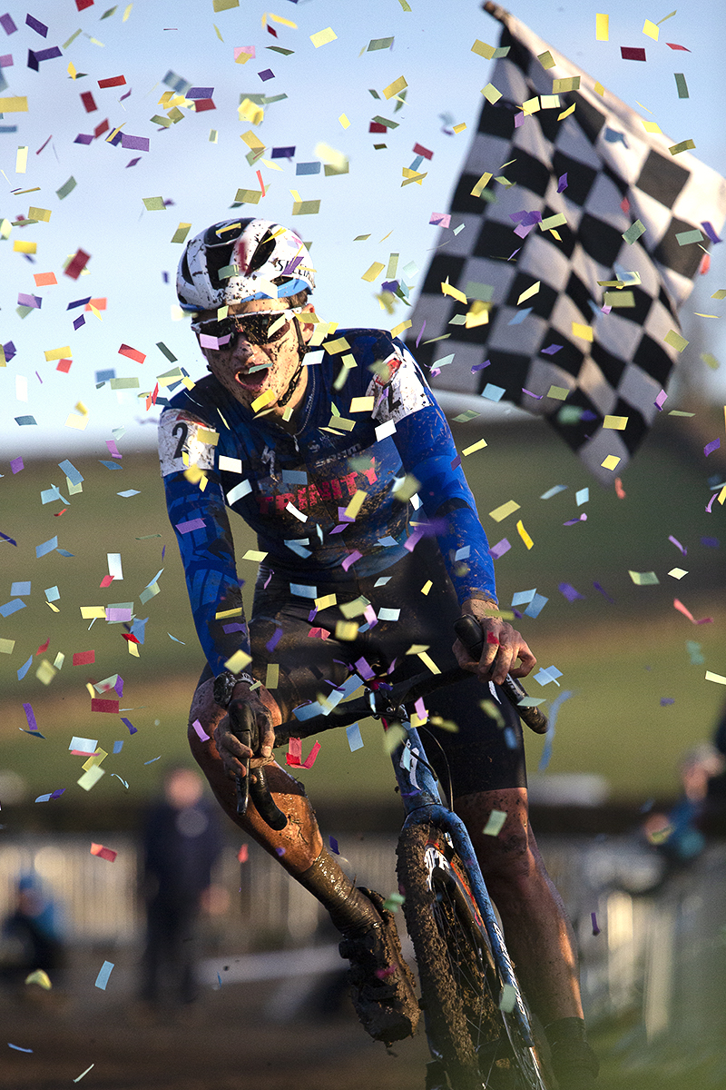 British National Cyclo-Cross Championships 2023 - Cameron Mason rides through confetti on the finish line with the chequered flag in the background