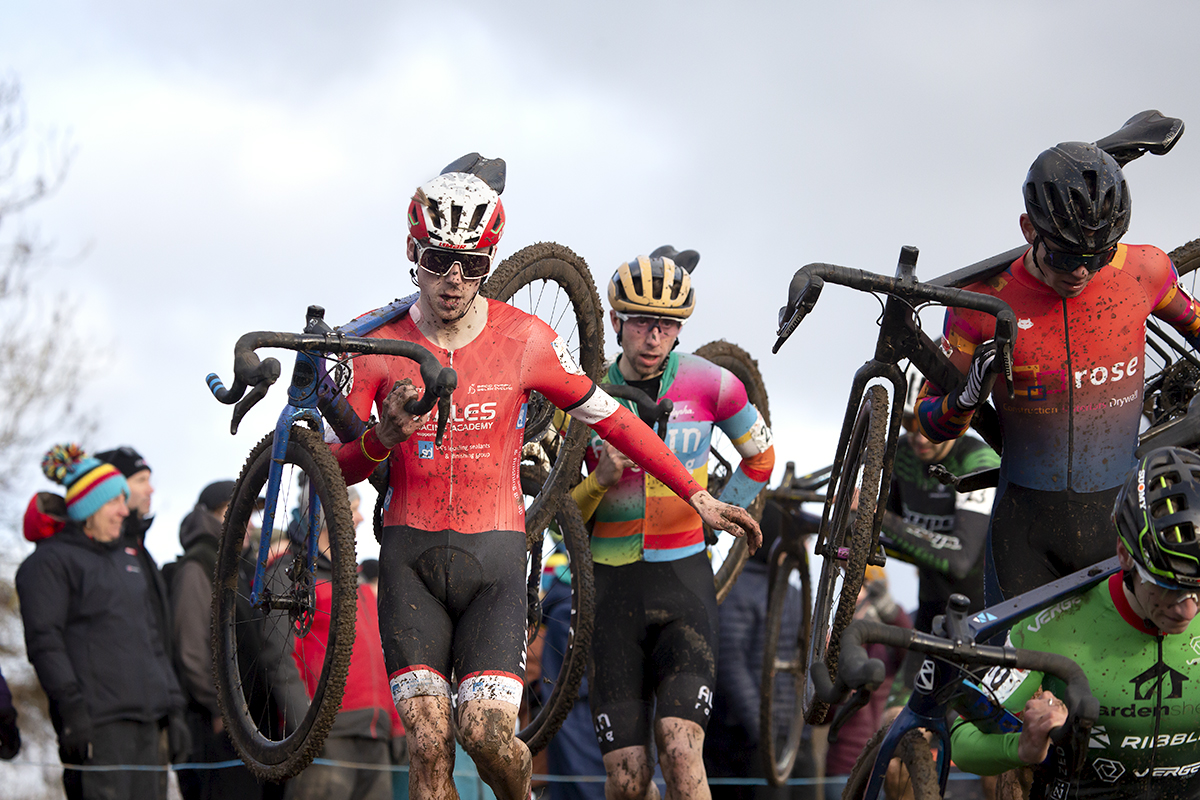 British National Cyclo-Cross Championships 2023 - Huw Buck Jones in a group of riders carries his bike down a steep muddy slope