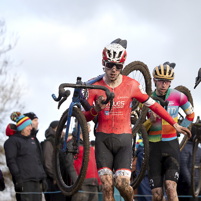 British National Cyclo-Cross Championships 2023 - Huw Buck Jones in a group of riders carries his bike down a steep muddy slope