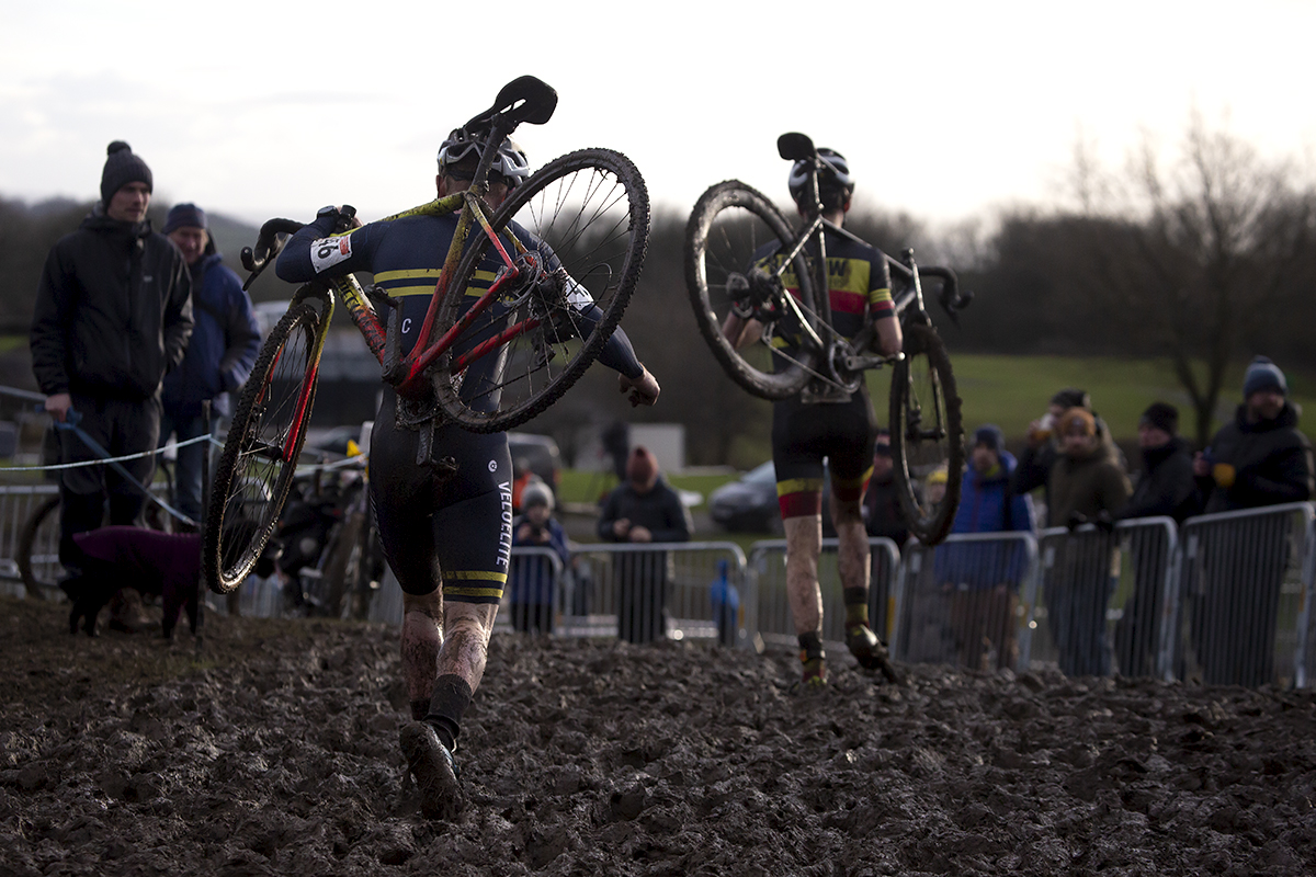 British National Cyclo-Cross Championships 2023 - Michael Burke & George Baker run with their bikes on their shoulders through deep mud on the course