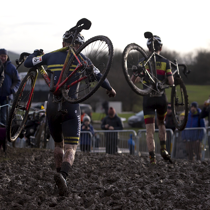 British National Cyclo-Cross Championships 2023 - Michael Burke & George Baker run with their bikes on their shoulders through deep mud on the course