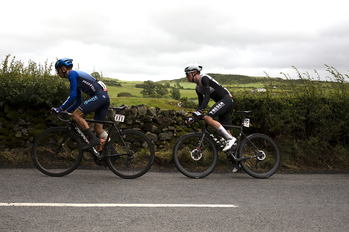 British National Road Championships 2022 - Men’s Road Race - Zappi Racing Team’s Ben Granger and Charlie Beake of Team Tor 2000 Kalas pass a dry stone wall with the countryside in the background