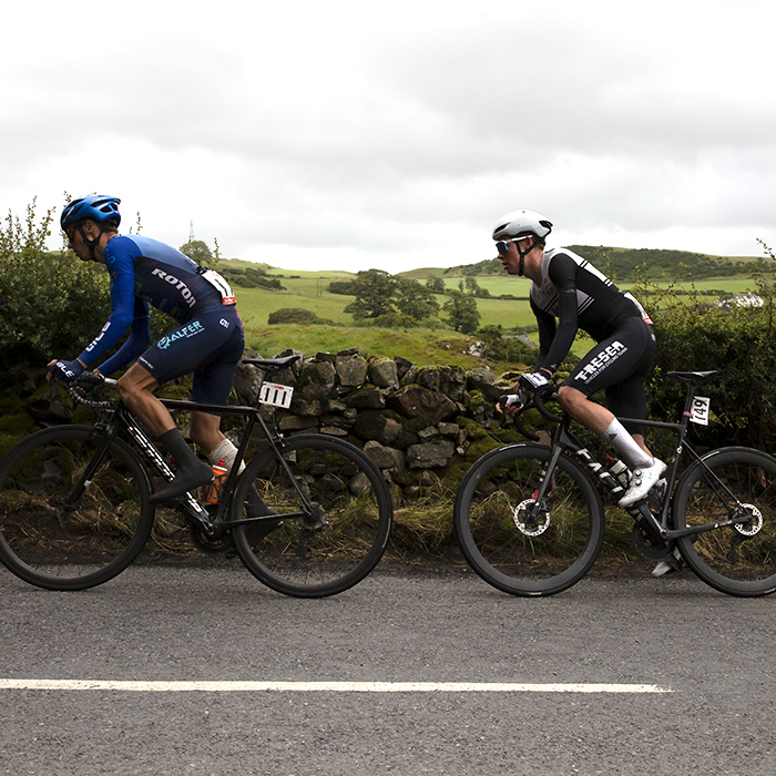 British National Road Championships 2022 - Men’s Road Race - Zappi Racing Team’s Ben Granger and Charlie Beake of Team Tor 2000 Kalas pass a dry stone wall with the countryside in the background