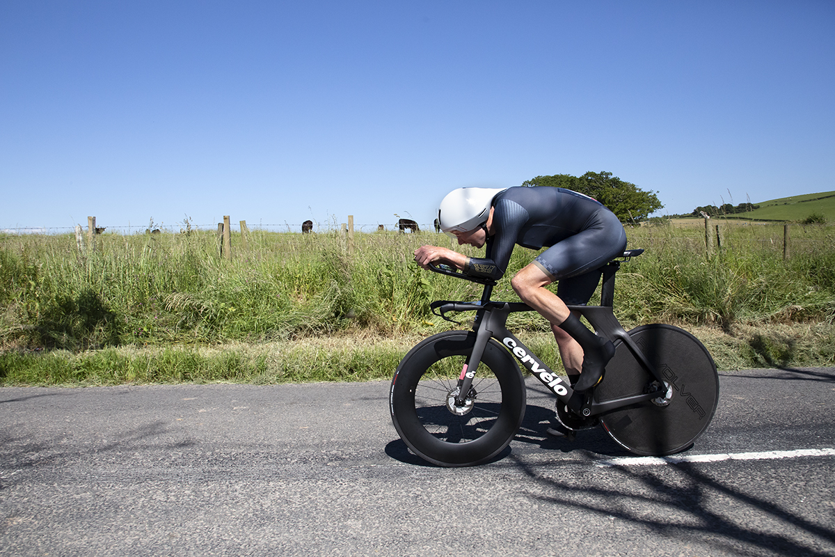 British National Road Championships 2022 - Men’s Time Trial - John Archibald in an aero tuck rides past a field of cows