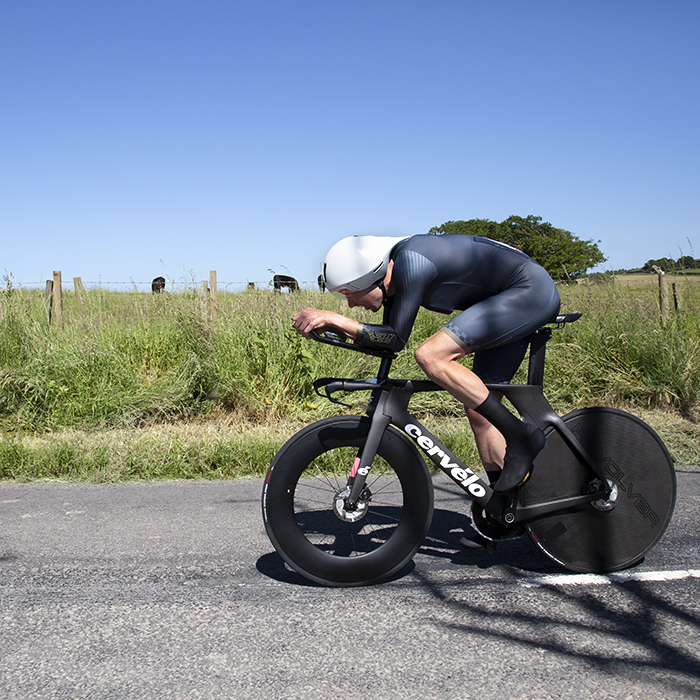 British National Road Championships 2022 - Men’s Time Trial - John Archibald in an aero tuck rides past a field of cows