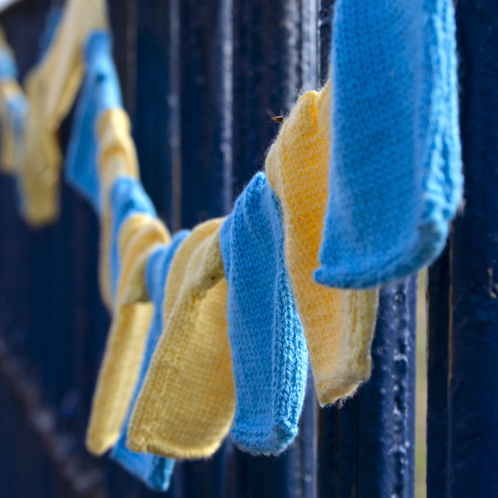 British National Road Championships 2023 - Bunting made of small yellow and blue knitted cycling jerseys hangs from railings