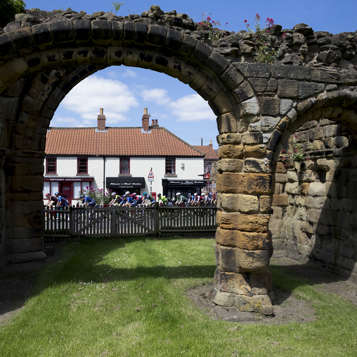 British National Road Championships 2024 - Men’s Road Race -The race is seen through an arch of Guisborough Priory as it passes through the town