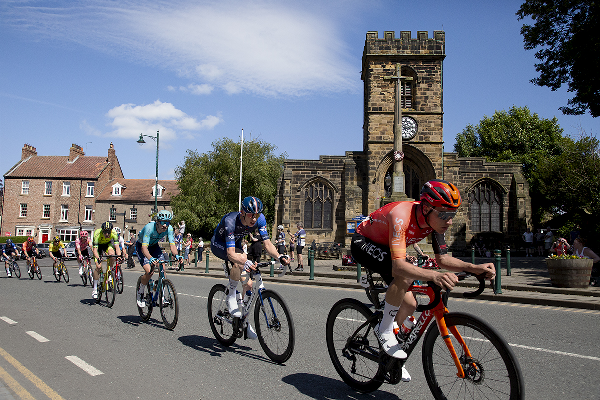 British National Road Championships 2024 - Men’s Road Race - The peloton passes by St Nicholas Church and war memorial in Guisborough