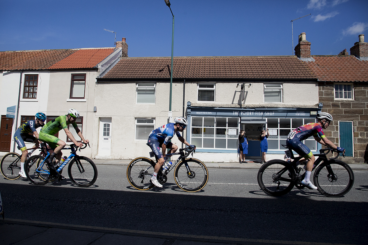 British National Road Championships 2024 - Men’s Road Race -Riders pass by a fish and chip shop as the staff watch the race