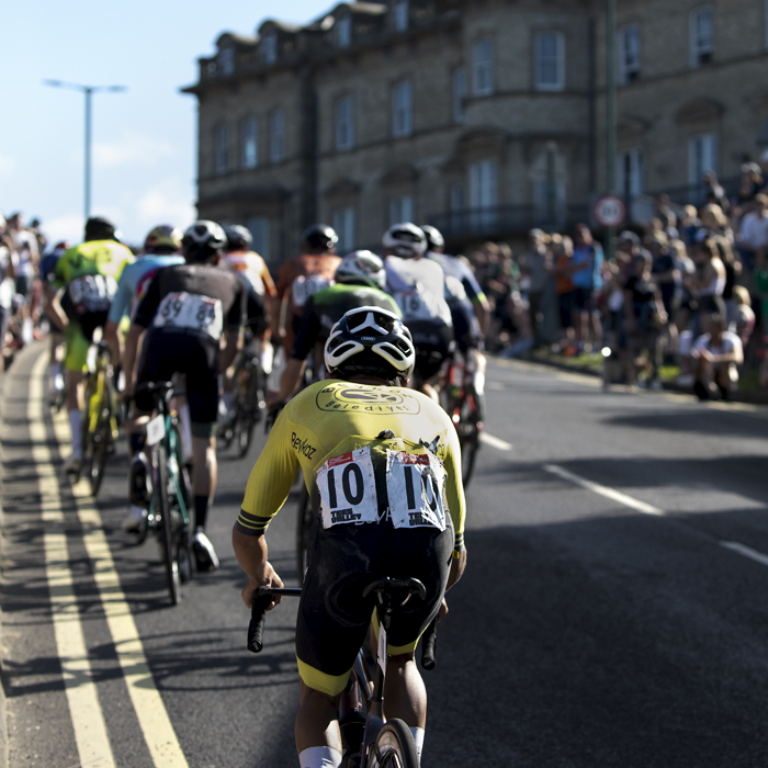 British National Road Championships 2024 - Men’s Road Race - Max Stedman follows a group of riders up the climb with a grand stone building to one side