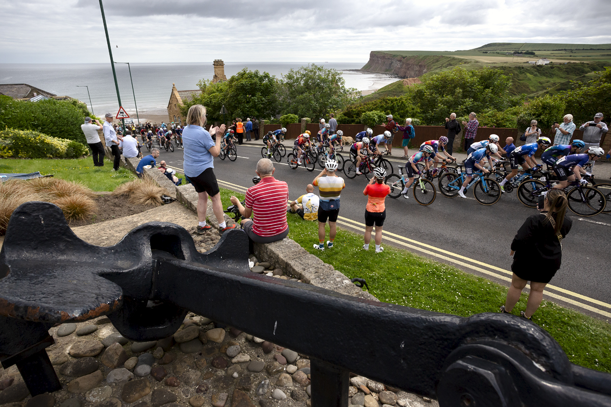 British National Road Championships 2024 - Women’s Road Race - A large ship’s anchor in the foreground as fans cheer the riders up the climb at Saltburn-by-the-Sea