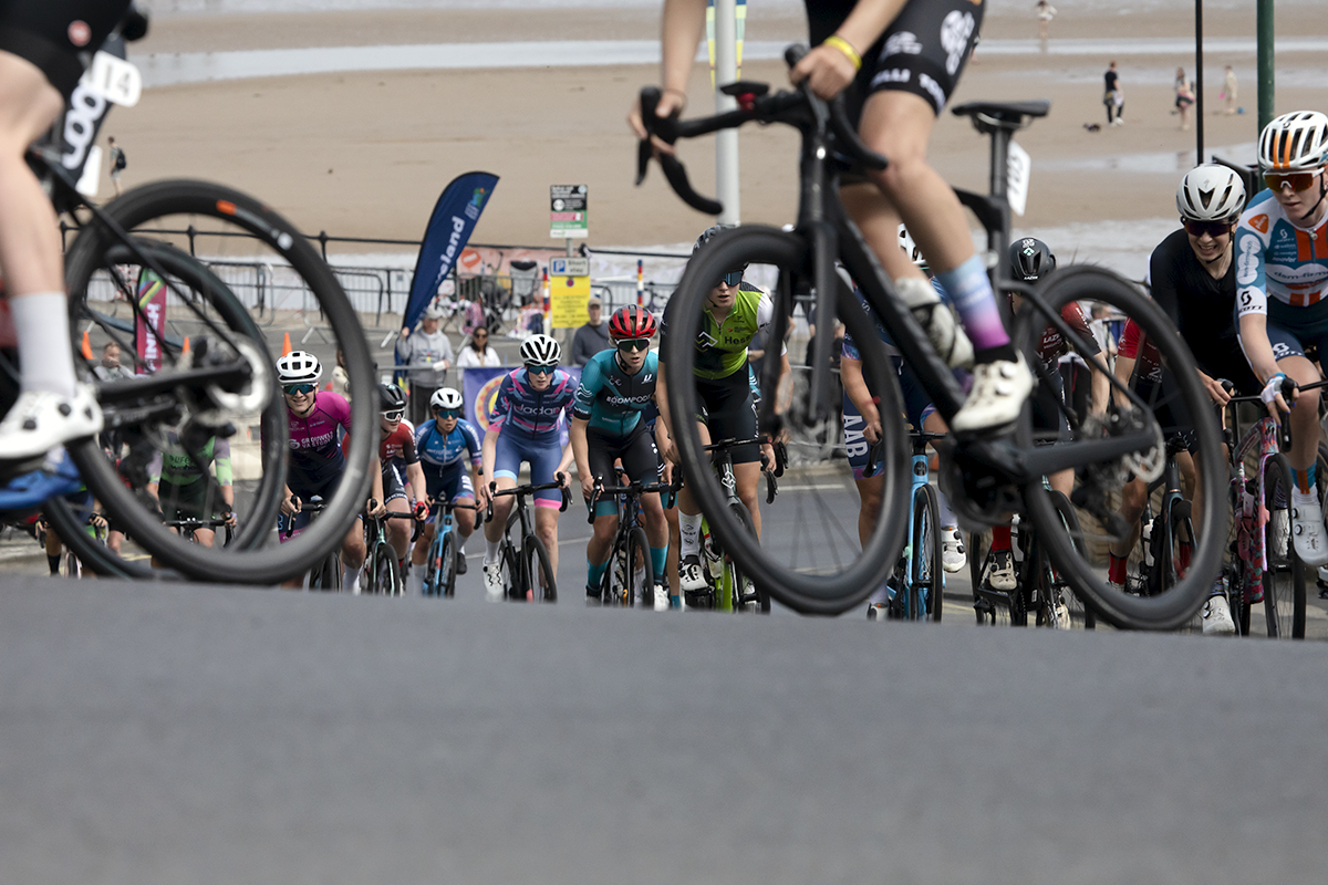 British National Road Championships 2024 - Women’s Road Race - Riders seen through a gap in bike wheels as they begin the climb at Saltburn