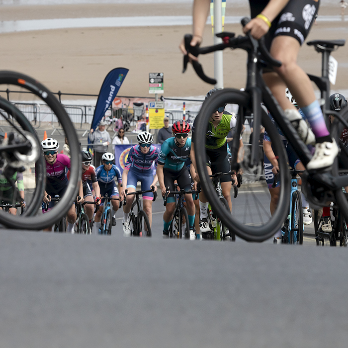 British National Road Championships 2024 - Women’s Road Race - Riders seen through a gap in bike wheels as they begin the climb at Saltburn