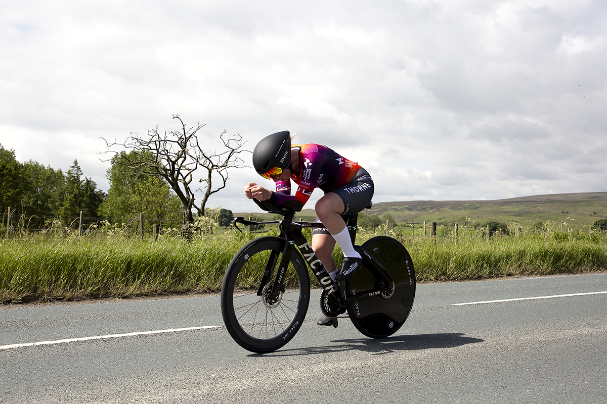 British National Road Championships 2024 -  Women’s Time Trial - Alice Wood of Human Powered Health passes by a gnarled leafless tree with open moorland in the distance