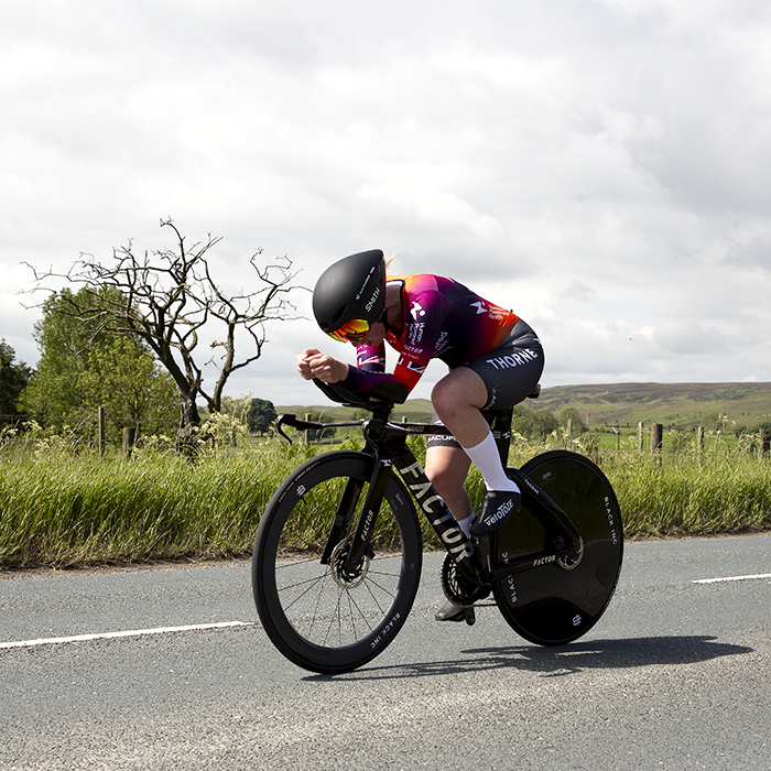 British National Road Championships 2024 -  Women’s Time Trial - Alice Wood of Human Powered Health passes by a gnarled leafless tree with open moorland in the distance