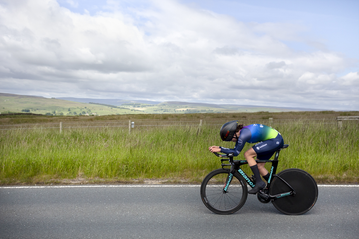 British National Road Championships 2024 -  Women’s Time Trial -Tamsin Miller in an aero tuck passes through countryside lit by the summer sun