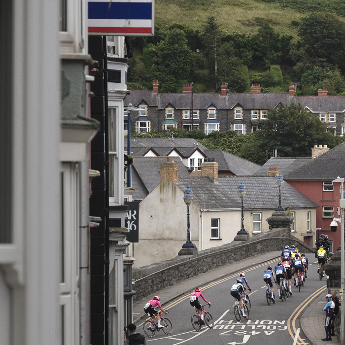 British National Road Championships 2025 - Road Race - Men - riders seen from behind as they cross a bridge in Aberystwyth