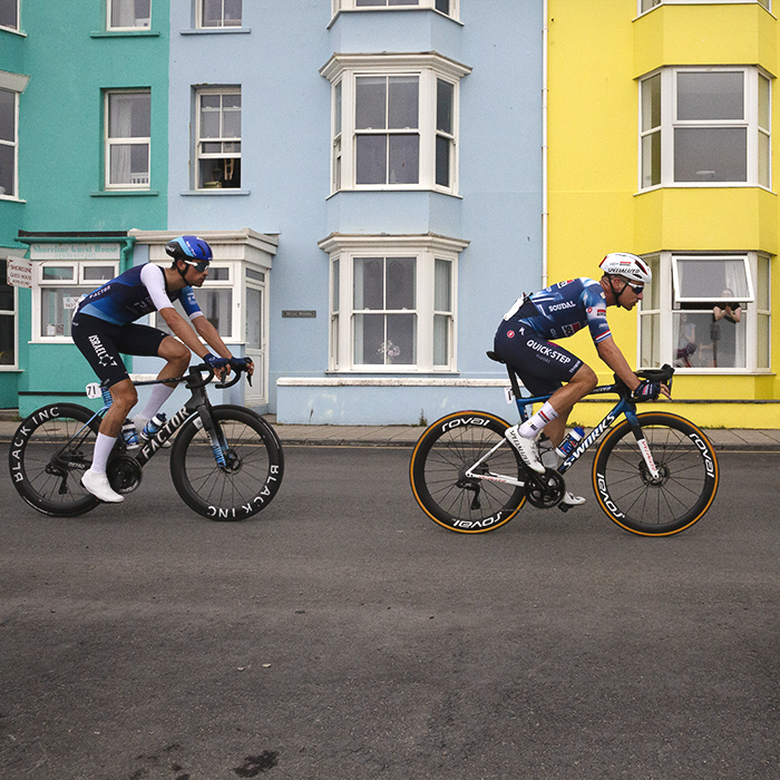 British National Road Championships 2025 - Road Race - Men - Road Race - Men - a small group of riders pass by colourful houses in Aberystwyth