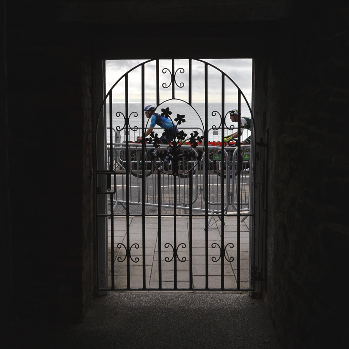 British National Road Championships 2025 - Road Race - Men - Euan Woodliffe & Oliver Wood seen through an ornate gate as they race down the sea front