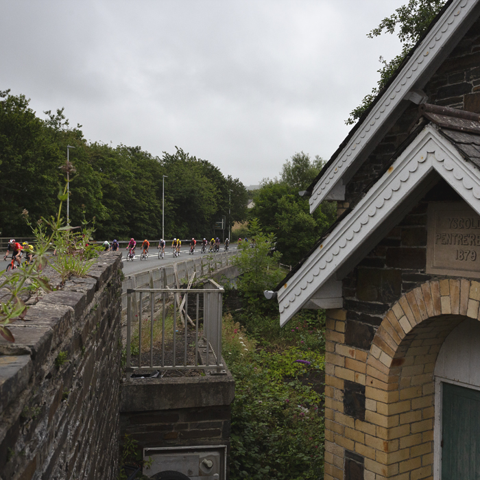 British National Road Championships 2025 - Road Race - Men - riders are strung out on the road in Llanfarian as they pass close to a small chapel