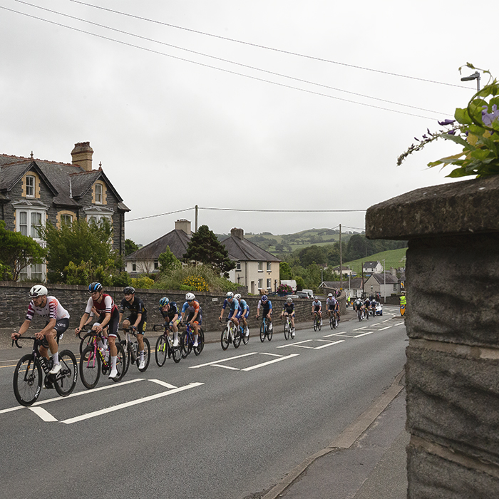 British National Road Championships 2025 - Road Race - Men - a group of riders race through the streets of Llanfarian