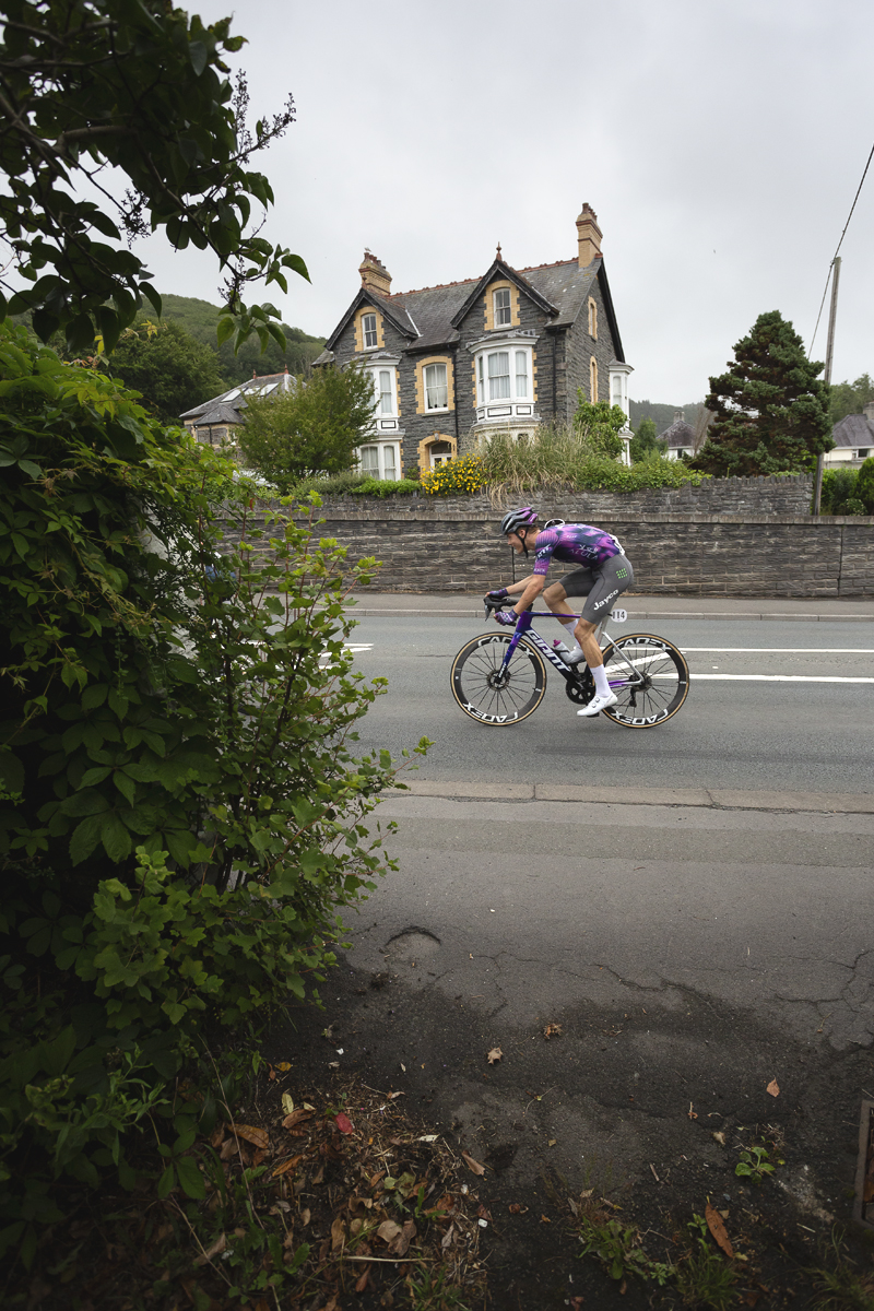 British National Road Championships 2025 - Road Race - Men - Robert Donaldson of Team Jayco AlUla passes a large stone built house