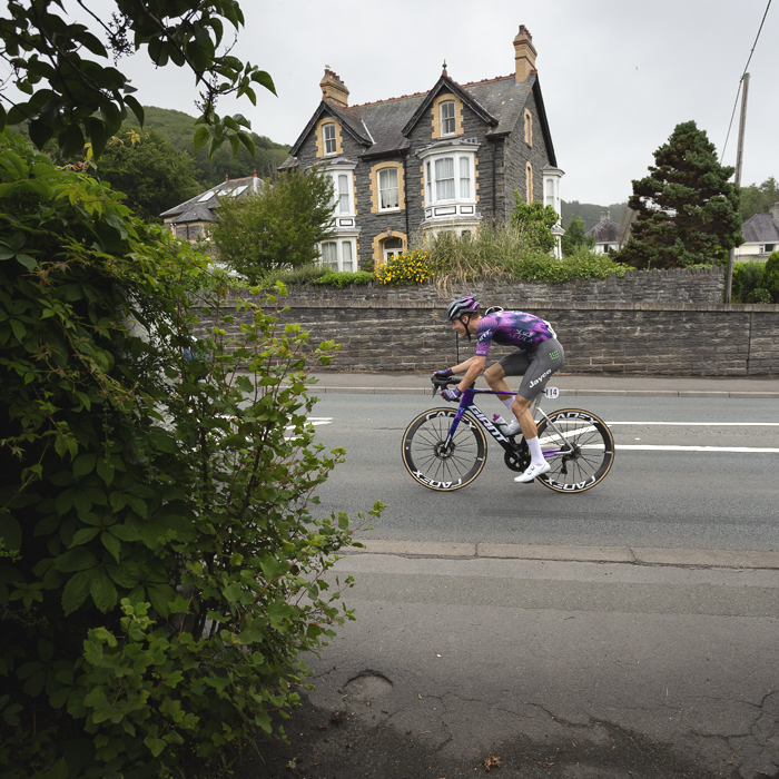 British National Road Championships 2025 - Road Race - Men - Robert Donaldson of Team Jayco AlUla passes a large stone built house