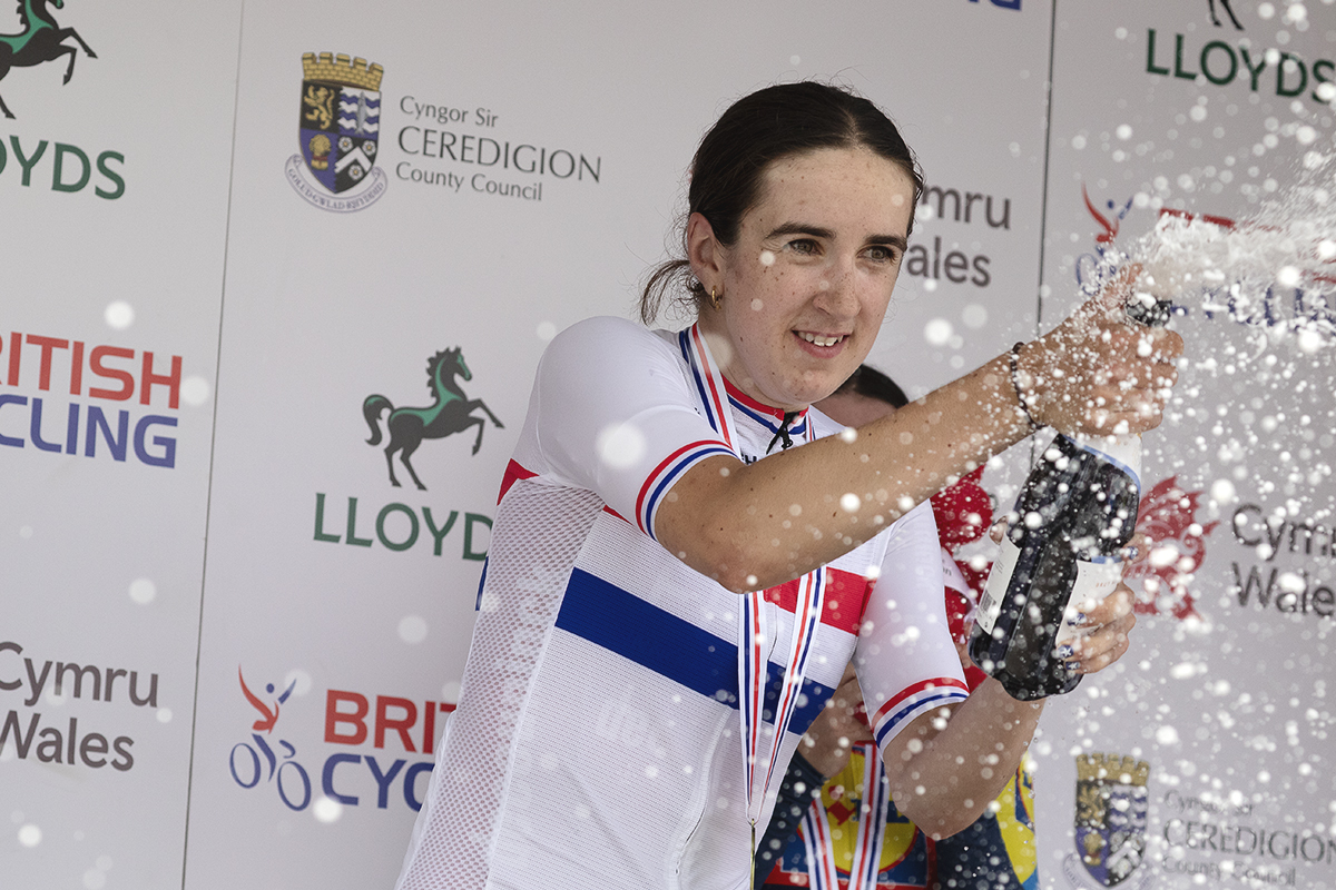 British National Road Championships 2025 - Road Race - Women - Millie Couzens, wearing the National Champions jersey sprays sparkling wine from the podium to celebrate her victory