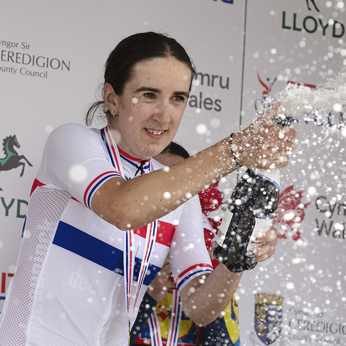British National Road Championships 2025 - Road Race - Women - Millie Couzens, wearing the National Champions jersey sprays sparkling wine from the podium to celebrate her victory