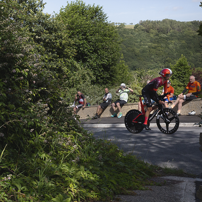 British National Road Championships 2025 - Time Trial - Elite Men - Sam Watson of Ineos Grenadiers is watched by a group of amateur cyclists from a wall at the roadside
