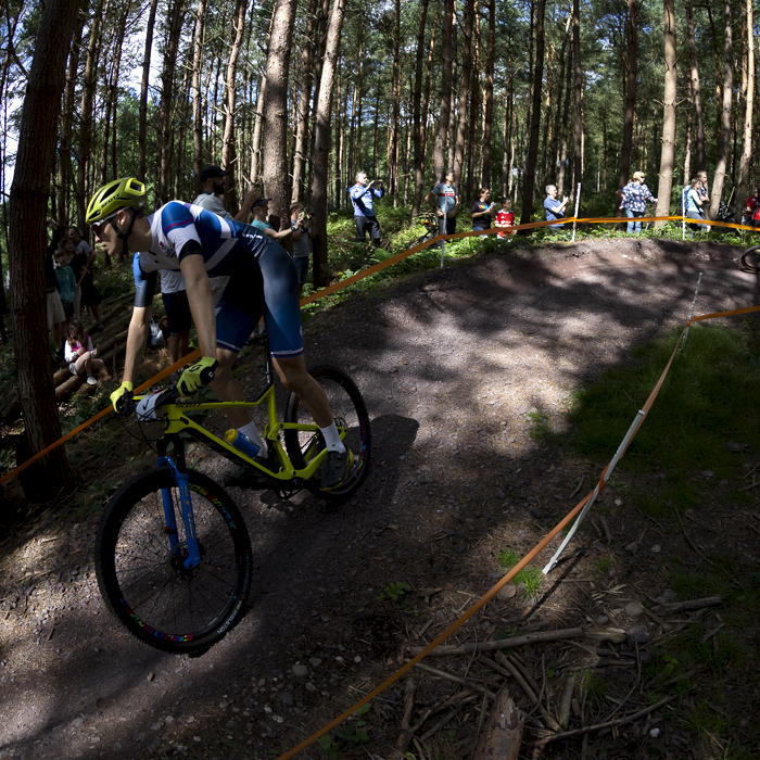 Birmingham 2022 - XXII Commonwealth Games - Mountain Bike - Men - Charlie Aldridge of Scotland is lit by patches of light through the canopy.