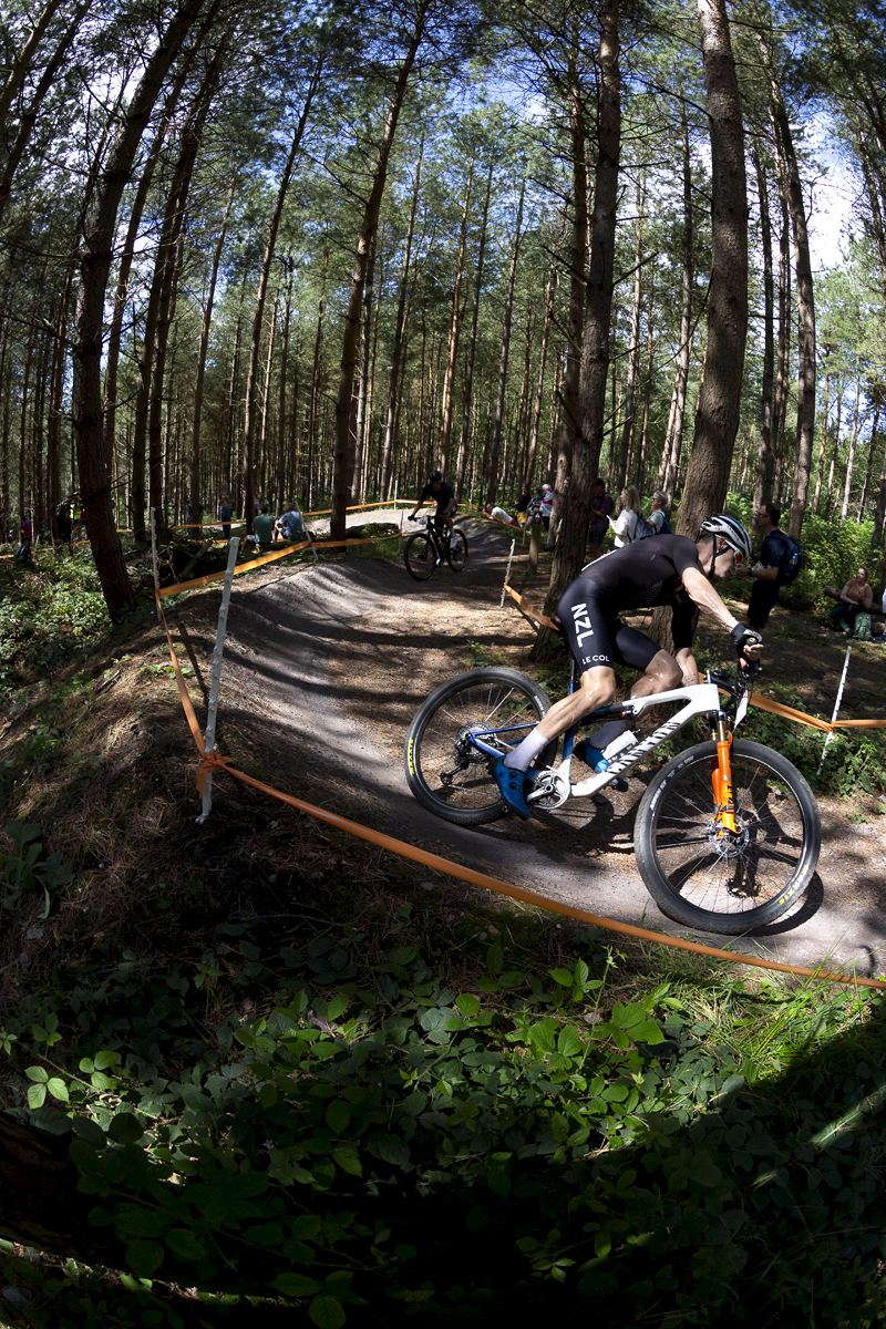 Birmingham 2022 - XXII Commonwealth Games - Mountain Bike - Men - Sam Gaze of New Zealand lit by sunlight through the trees races through the forest