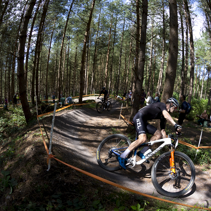 Birmingham 2022 - XXII Commonwealth Games - Mountain Bike - Men - Sam Gaze of New Zealand lit by sunlight through the trees races through the forest